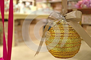 Closed up a glitter gold round shaped Christmas ornament with gold ribbon