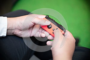 Closed up of guy`s hands playing on the red game console. a wireless console controller. Enjoying free time concept. Preoccupied