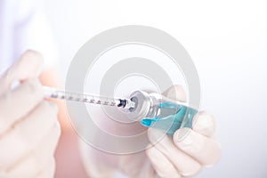 Closed up hand of Nurse fills syringe from injection vial