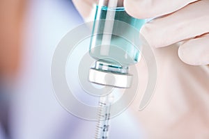 Closed up hand of Nurse fills syringe from injection vial on white