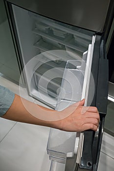 Closed up hand opening the silver color handle of refrigerator d