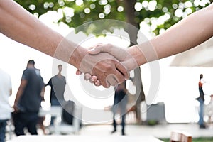 Closed up of hand shake with people in background. Business Coop