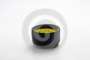 Closed up macro object, Isolate heap of extracted Green Tea Powder in black ceramic bowl white background. This is best natural in