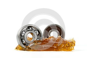 Closed up macro, two ball bearing put into yellow transparent lithium grease isolated on white background with copy space,