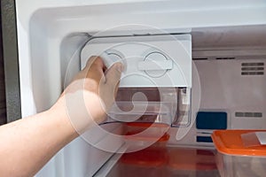 Closed up man hand twisting for ice from the ice maker photo