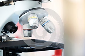 Closed up of microscope in the laboratory with orange light and blurred background.