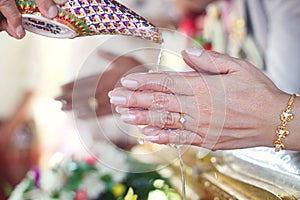 Closed-up pouring blessing water on bride's bands,Thai wedding ceremony