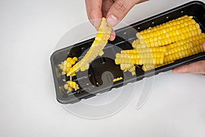 Closed up slimy string of spoiled corn in black plastic container kept too long in fridge.