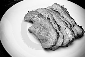 Closed up of tender smoked and grilled beef sliced on white plate. Beef sliced. Western traditional food. Black and white tone