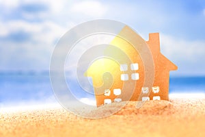 Closed up tiny home models on sand with sunlight and beach background