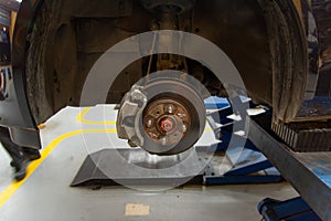 Closed up of wheel vehicle repair and maintenance suspension ,disk brake automobile parts under a lifted auto in modern garage car