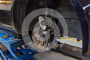 Closed up of wheel vehicle repair and maintenance suspension ,disk brake automobile parts under a lifted auto in modern garage car