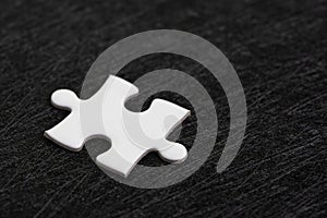 Closed up of white jigsaw puzzle on dark black background using as answer, solution, completion or strategy for business success