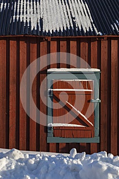 Closed window blinds of red wooden cabin in snow, Z-shaped texture