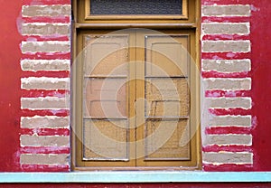 Closed window in a house with a red wall.