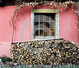 Closed window on a pink wall and a woodpile