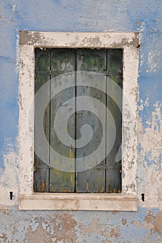 Closed window with shutter on blue wall