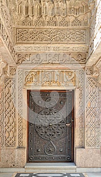 Closed wooden aged door with ornate bronzed floral patterns