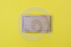 Closed wooden box with place for you logo on yellow colored paper background. top view