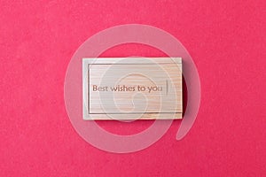 Closed wooden box on red colored paper background with inscription best wishes to you on top