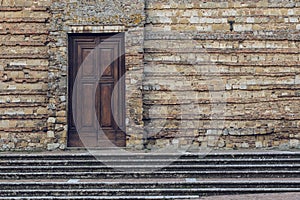 Closed wooden door on ancient stone wall facade