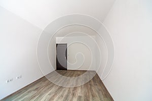 Closed wooden door in empty bright room. New home interior. Wooden floor. White walls