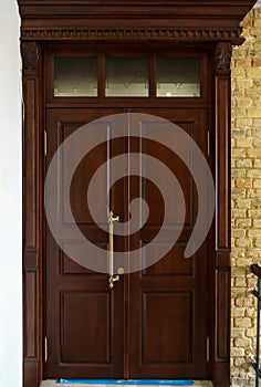 A closed wooden door inside. Interior design, dark red door with metal handle and lock. Evacuation exit