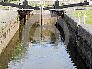 Closed wooden lock gates on the calder and hebble navigation canal in brighouse reflected in the water