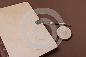 Closed wooden notebook with wooden pen on brown background with place for you logo