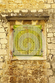 Closed wooden window and shutters in stone wall.