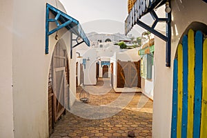 Closed wooden Windows and doors in single- story houses. An empty street of a small Arab market. The shopping street of the hotel