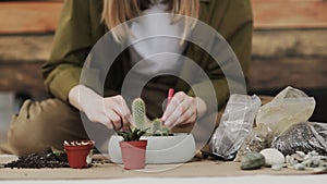 Closedup of woman`s hands gardener pours the soil with a shovel into a new ceramic pot for transplanting houseplant on