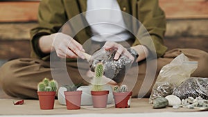 Closedup of woman`s hands gardener pours the soil with a shovel into a new ceramic pot for transplanting houseplant on