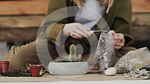 Closedup of woman`s hands gardener pours the soil with a shovel into a new ceramic pot for transplanting houseplant on