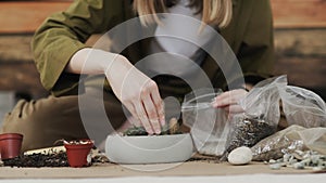 Closedup of woman`s hands gardener pours the soil with a shovel into a new ceramic pot for transplanting houseplant on