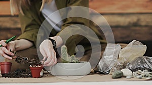 Closedup of woman`s hands gardener pours the soil with a shovel into a new ceramic pot for transplanting houseplant on