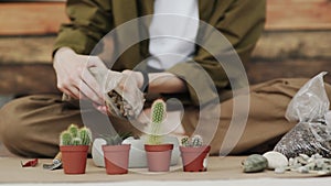 Closedup of woman`s hands gardener pours the soil with a shovel into a new ceramic pot for transplanting houseplant on