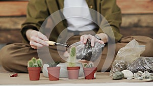 Closedup of woman`s hands gardener pours the soil with a shovel into a new ceramic pot for transplanting houseplant on