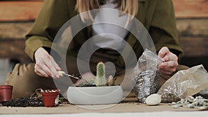 Closedup of woman`s hands gardener pours the soil with a shovel into a new ceramic pot for transplanting houseplant on