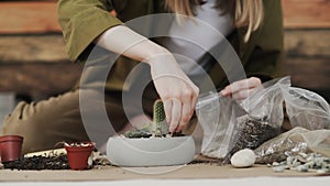 Closedup of woman`s hands gardener pours the soil with a shovel into a new ceramic pot for transplanting houseplant on