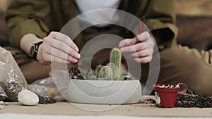 Closedup of woman`s hands gardener pours the soil with a shovel into a new ceramic pot for transplanting houseplant on