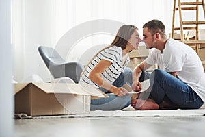 Closeness of the people. Cheerful young couple in their new apartment. Conception of moving