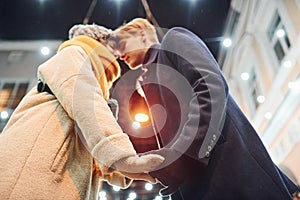 Closeness of the people. Happy young couple in warm clothes is on christmas decorated street together