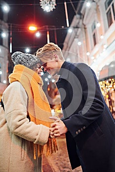 Closeness of the people. Happy young couple in warm clothes is on christmas decorated street together