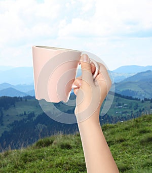 Closeness to nature. Woman holding cup in mountains, closeup