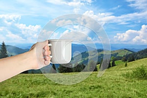 Closeness to nature. Woman holding cup in mountains, closeup