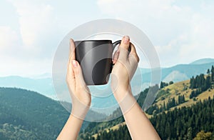 Closeness to nature. Woman holding cup in mountains, closeup