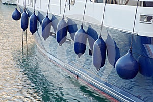 Closep of blue fenders hanging on blue and white boat in the harbor in Malta