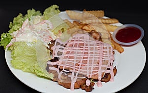 Closep shot of pork with pink sauce and french fries