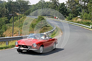 Closer up Classic little red italian sports car on downhill road